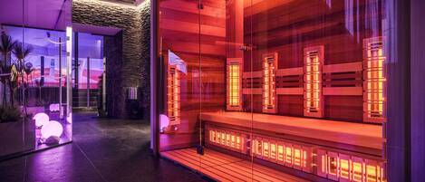 A modern spa area with glass walls, wooden benches, and ambient lighting.