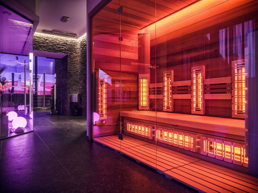 Un moderno espacio de spa con paredes de vidrio, bancos de madera e iluminación ambiental.