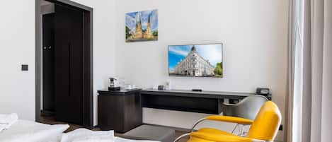 Una habitación de hotel con cama, escritorio, silla y televisor.