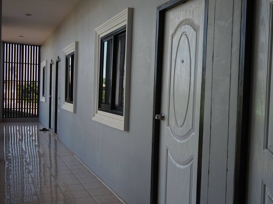 A hallway with doors and windows, a tiled floor, and a metal gate in the background.