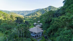 Un resort con edificios de techo de paja rodeado de exuberante vegetación y colinas.