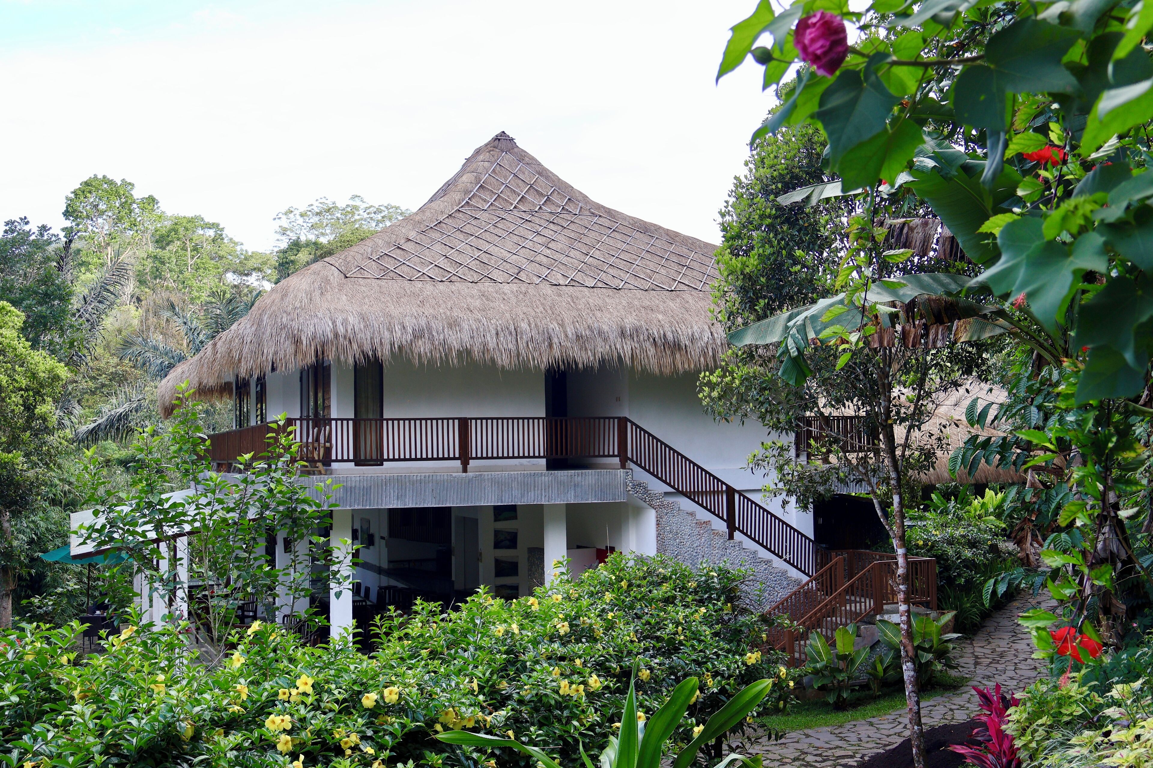 A two-story building with a thatched roof and a balcony.