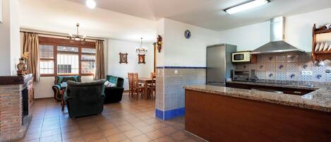 A spacious living area with a fireplace, a dining table, and a kitchen area with modern appliances.