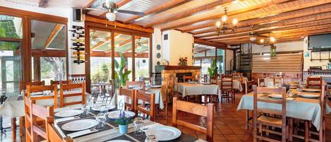 A restaurant with wooden tables and chairs, a ceiling fan, and a view of the outdoors.