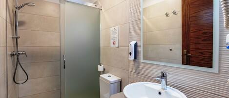 Une salle de bain moderne avec une douche à parois de verre, des toilettes, un lavabo et un miroir.