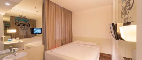 A hotel room with a bed, a bathroom with a sink and mirror, a TV, and a wall with motivational text.