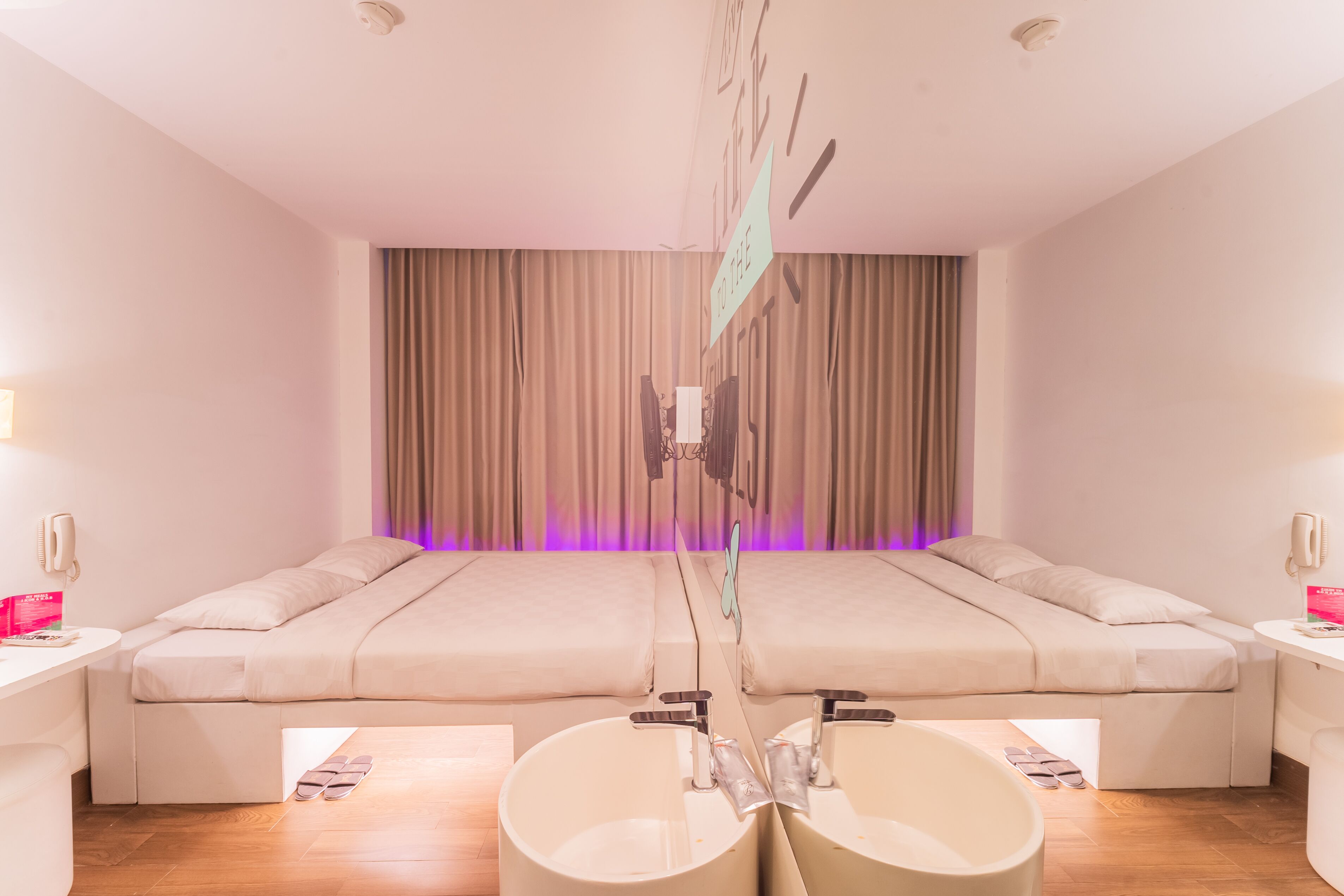 A hotel room with a large bed, two bedside tables, a desk, and a bathroom with a bathtub and sink.