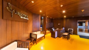 Ein Empfangsbereich mit Holzboden, einer Rezeption, einer Wartezone mit Sofas und einem an der Wand befestigten Schild für das 'Japanica Spa & Fitness Center'.