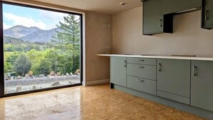 A modern kitchen with a large sliding glass door leading to a scenic outdoor view.