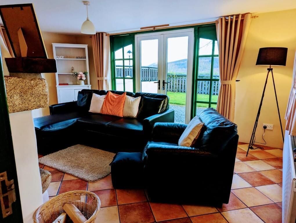 A living room with a sofa set, a lamp, and a view through a glass door.