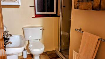 A compact bathroom with a toilet, sink, and shower.