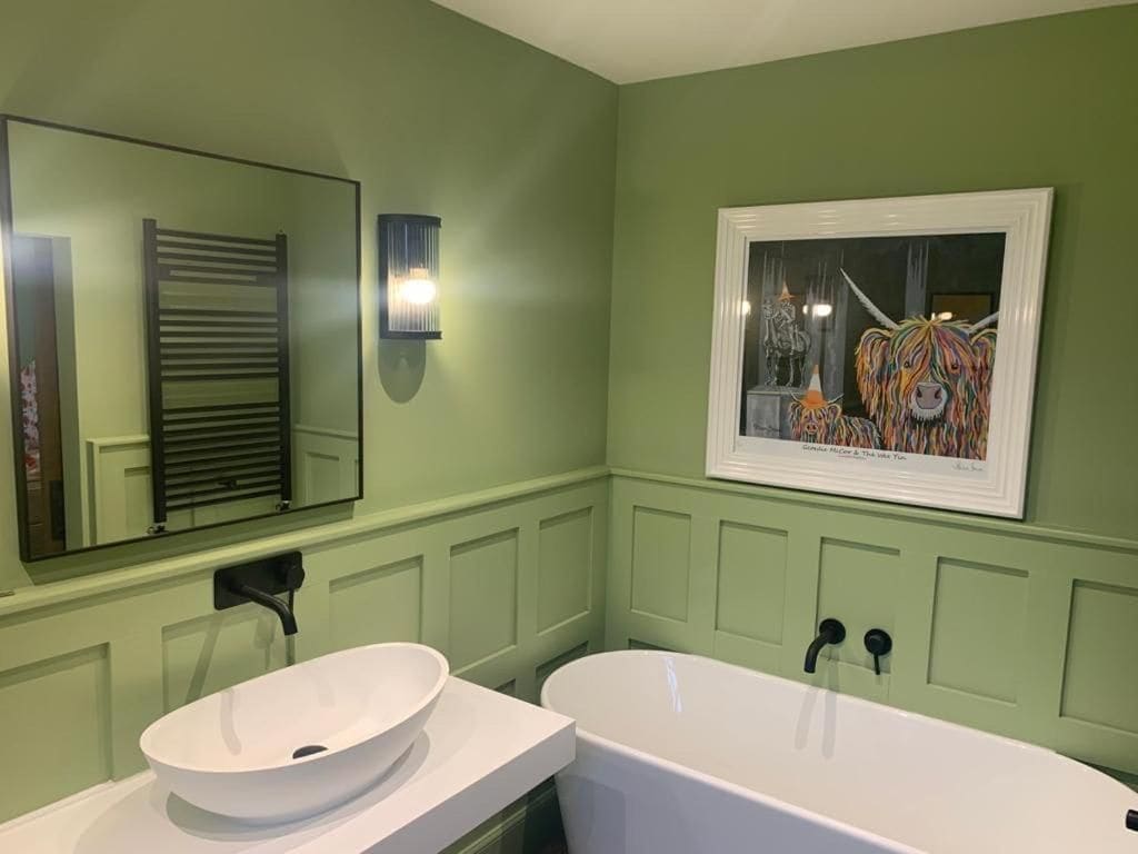A bathroom with a white sink, a bathtub, a mirror, and a framed picture on the wall.