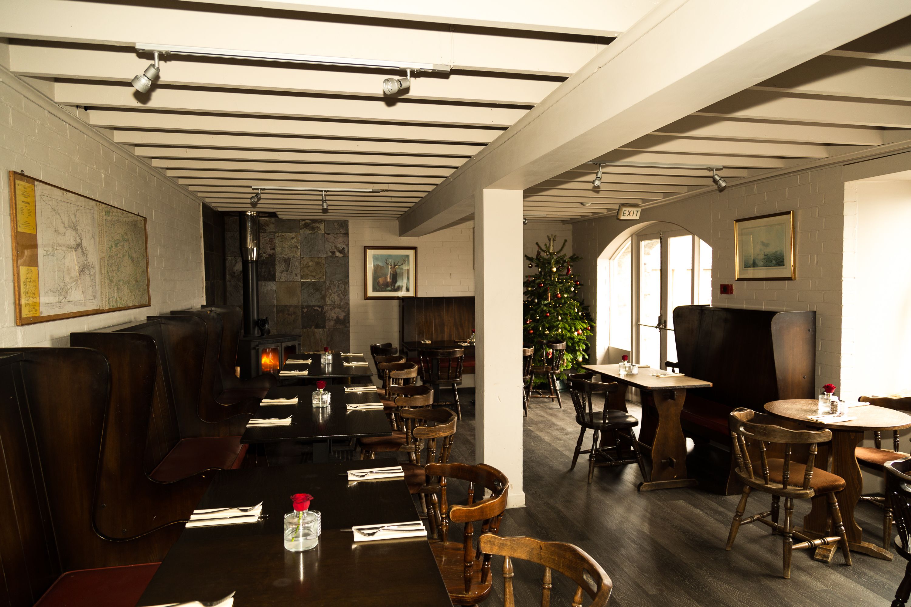 A restaurant with wooden booths and tables, a Christmas tree, and a fireplace.