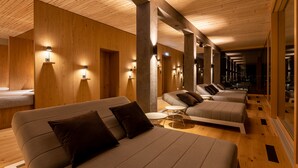 Un moderno vestíbulo de hotel con una larga recepción, varias zonas de estar con sofás y sillones, y un techo de madera.