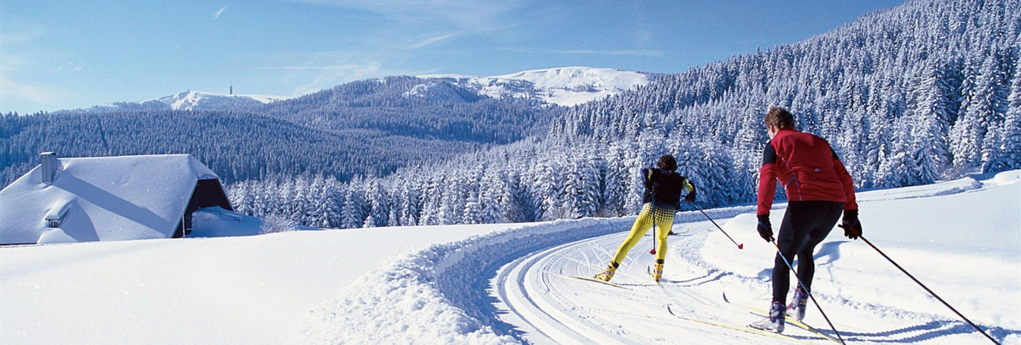 A snowy landscape with two skiers and a tent.