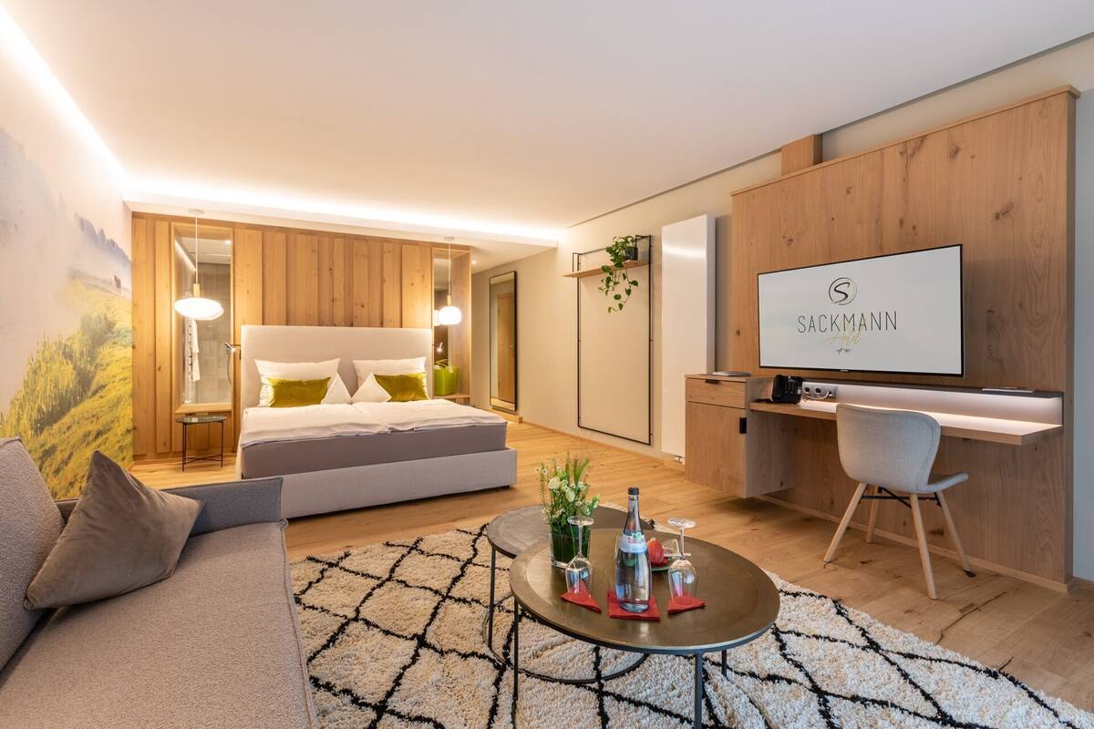 Ein modernes Hotelzimmer mit Bett, Sofa, Schreibtisch und Fernseher.