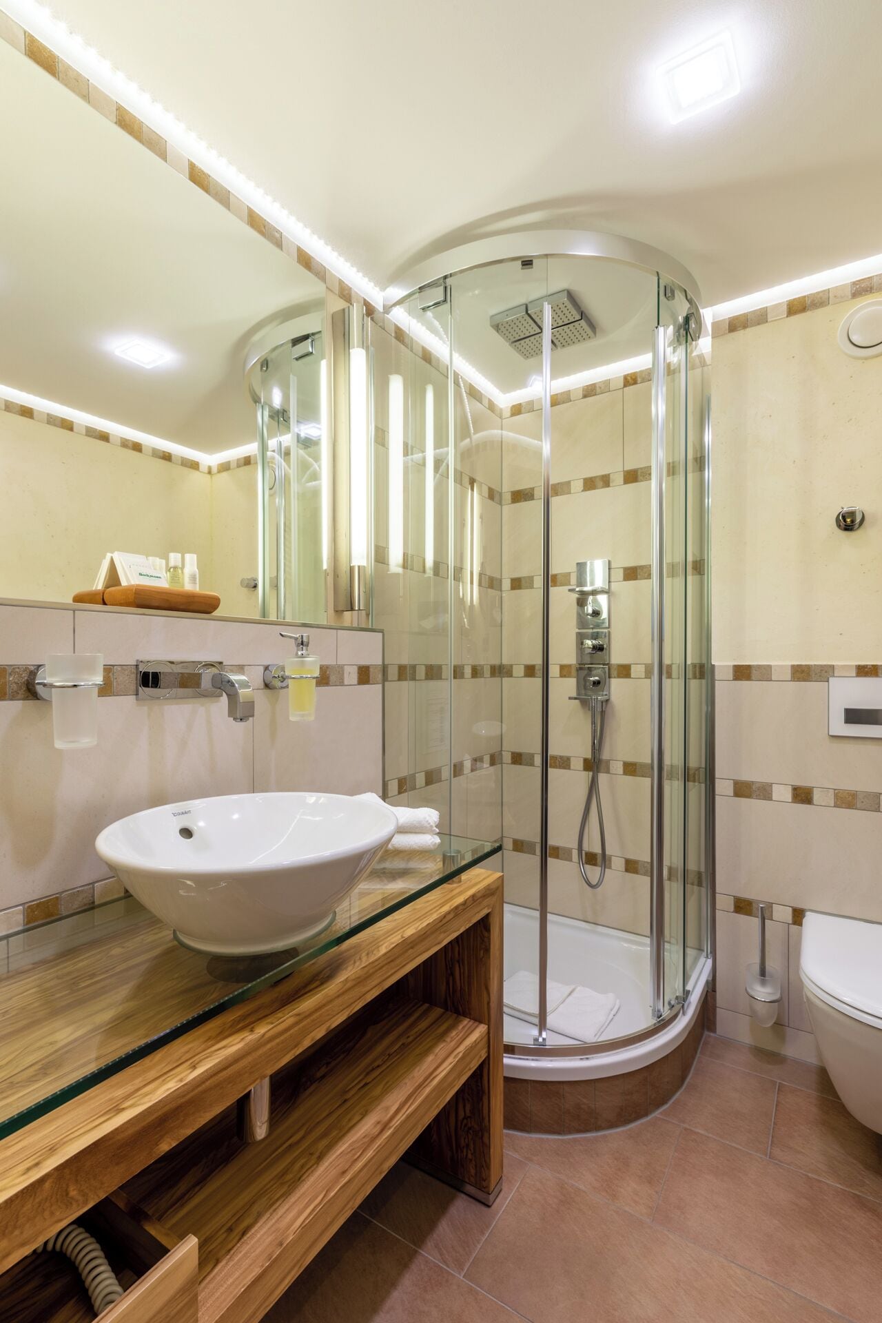 A modern bathroom with a glass-enclosed shower, a white sink, and a wooden vanity.