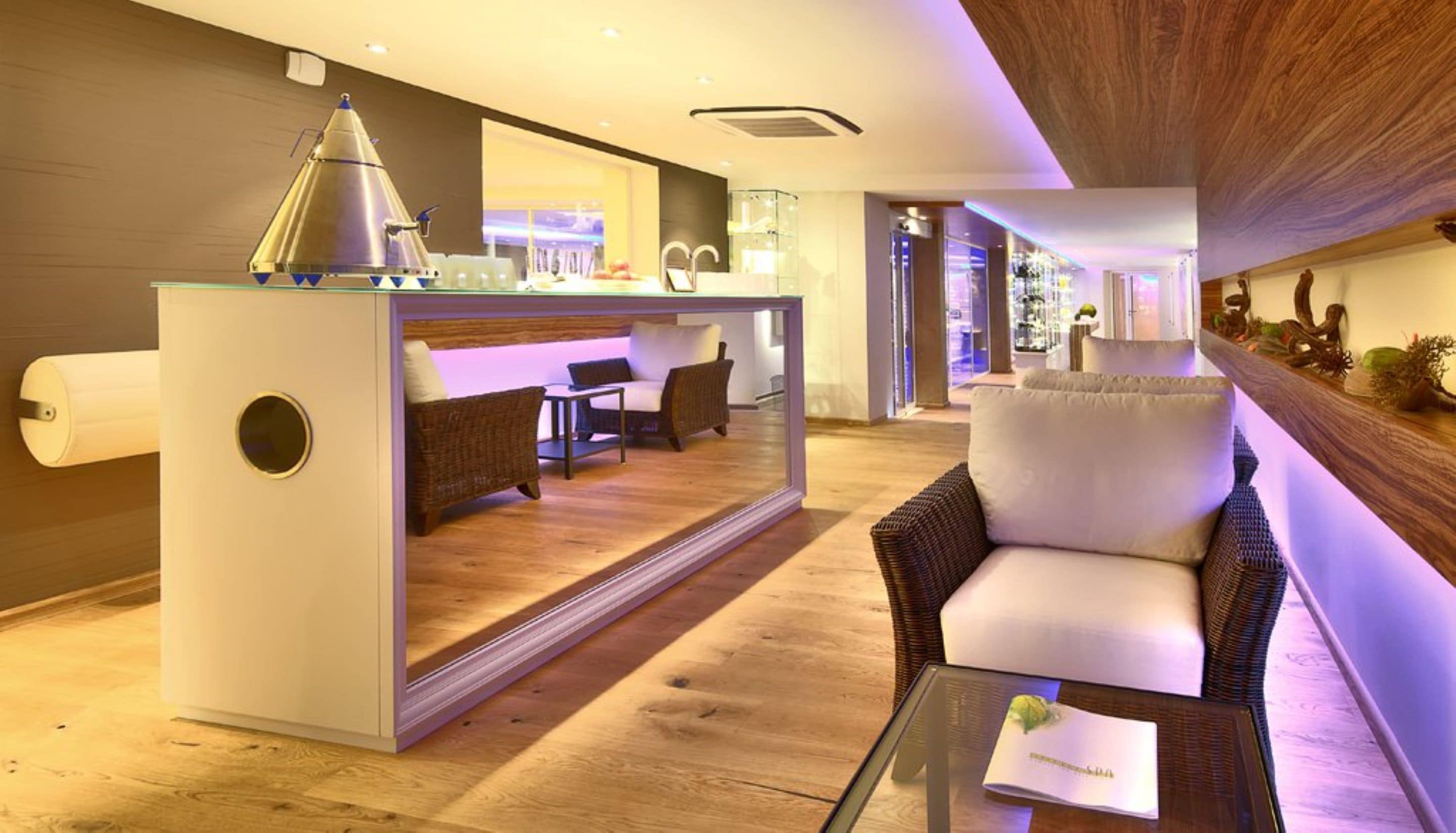 A modern hotel lobby with a central bar area, seating arrangements, and a reception desk.