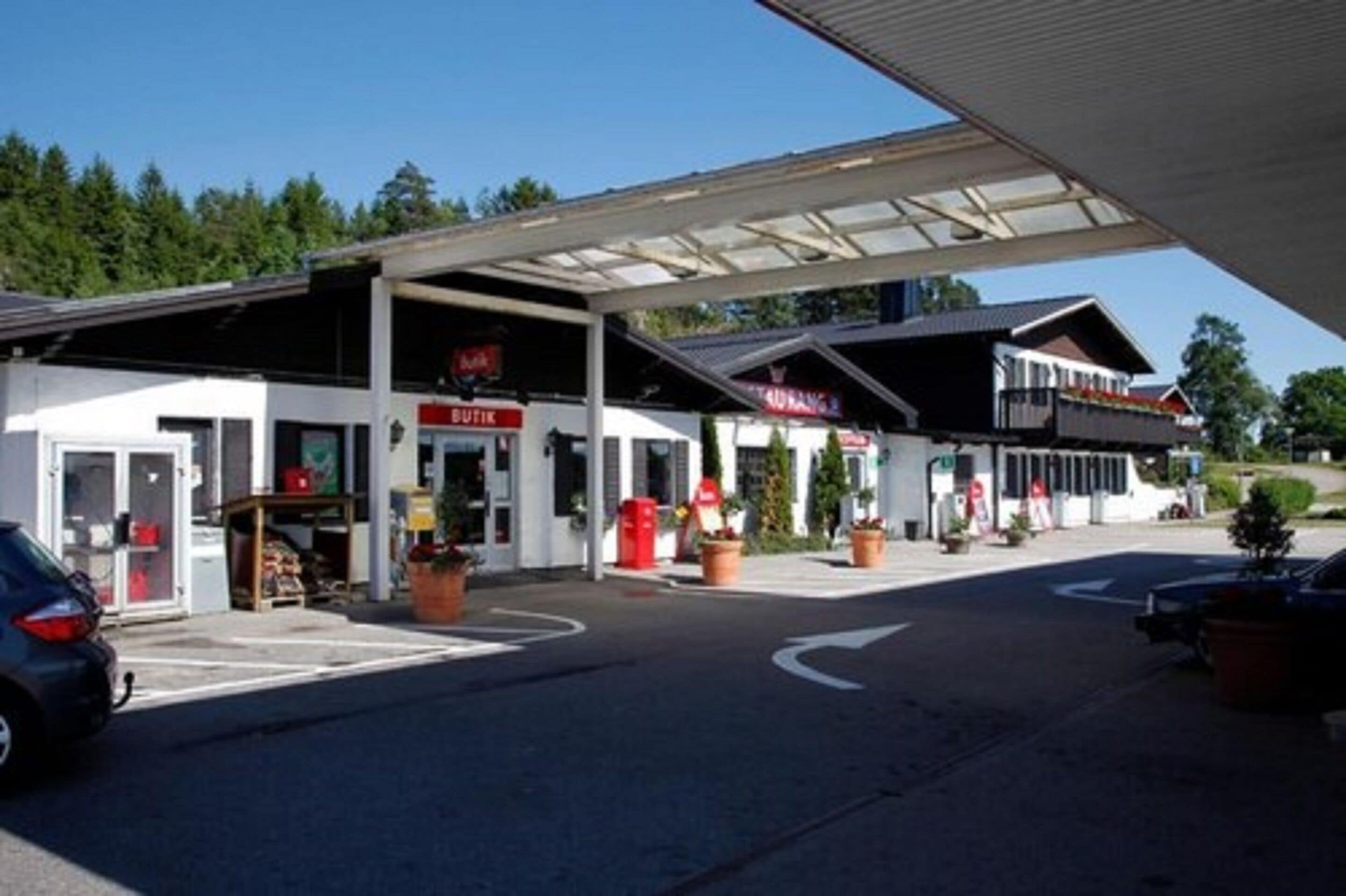 A gas station with multiple fuel pumps, a convenience store, and a small building with a balcony.