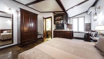 Un dormitorio con una cama grande, un armario de madera y una zona de kitchenette.