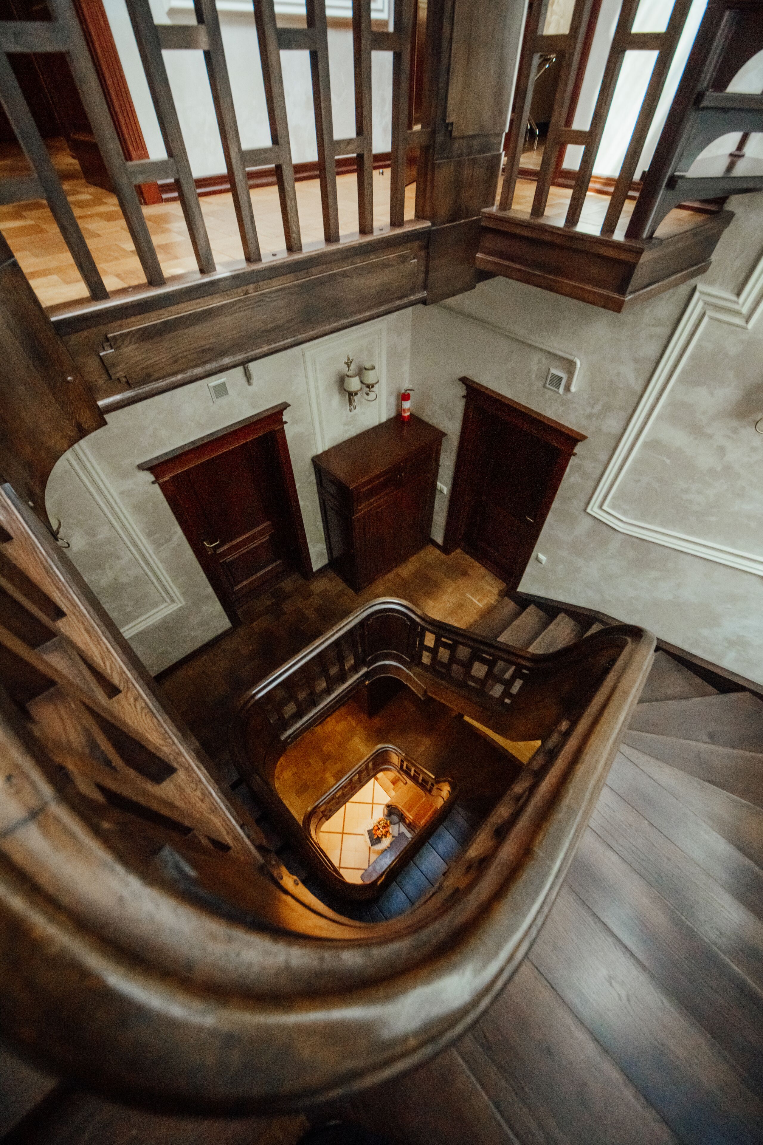 A multi-level wooden staircase with a central open area, possibly a lounge or waiting area, surrounded by wooden walls and furniture.