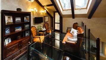 A modern living room with a glass railing, a wooden bookshelf, and a comfortable seating area.