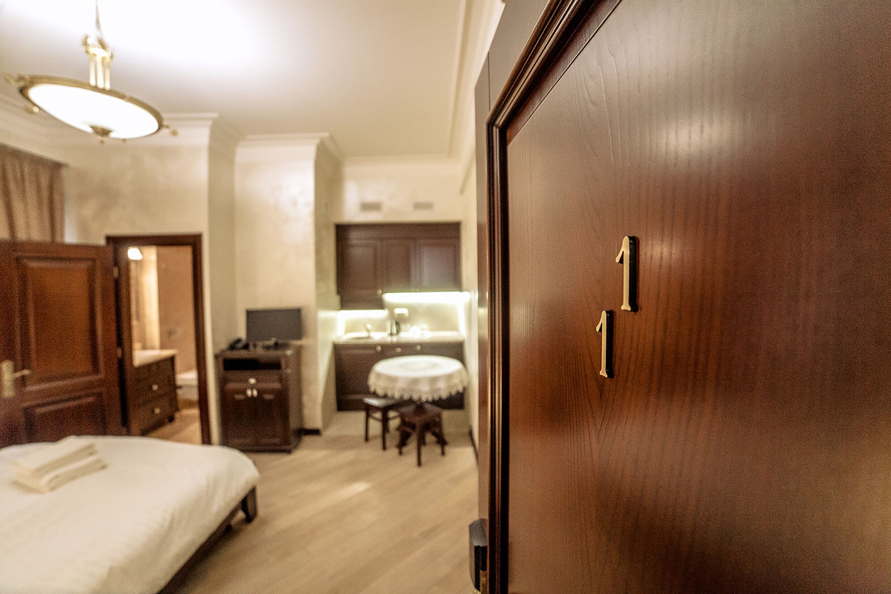 Quarto de hotel com uma cama, uma escrivaninha, uma cadeira e uma mesa redonda pequena.