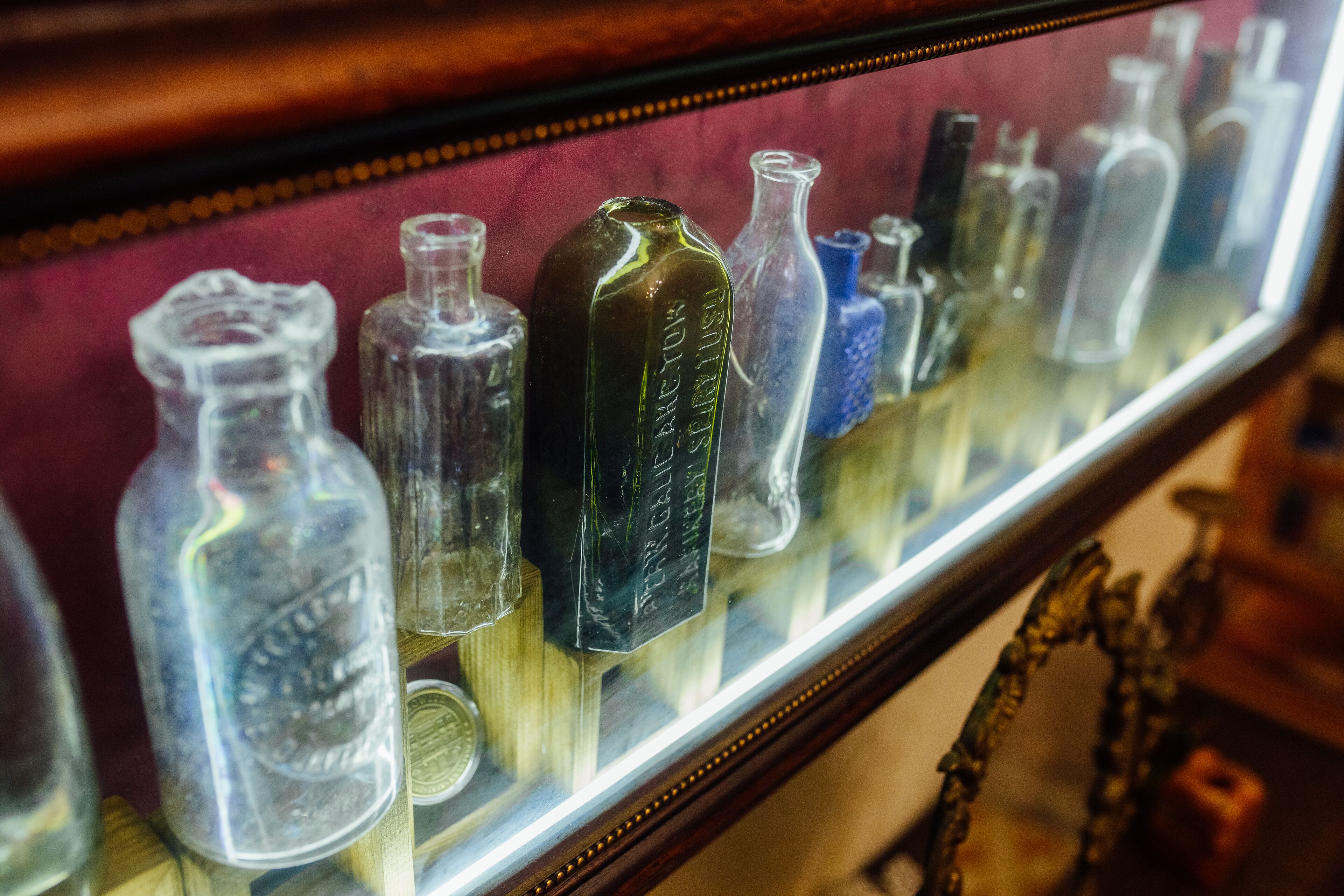 A display of antique glass bottles in a museum setting.