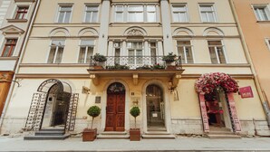 A historic building with a central entrance, arched doorways, and a balcony with flower boxes. - Apart-hotel Horowitz (Lviv)