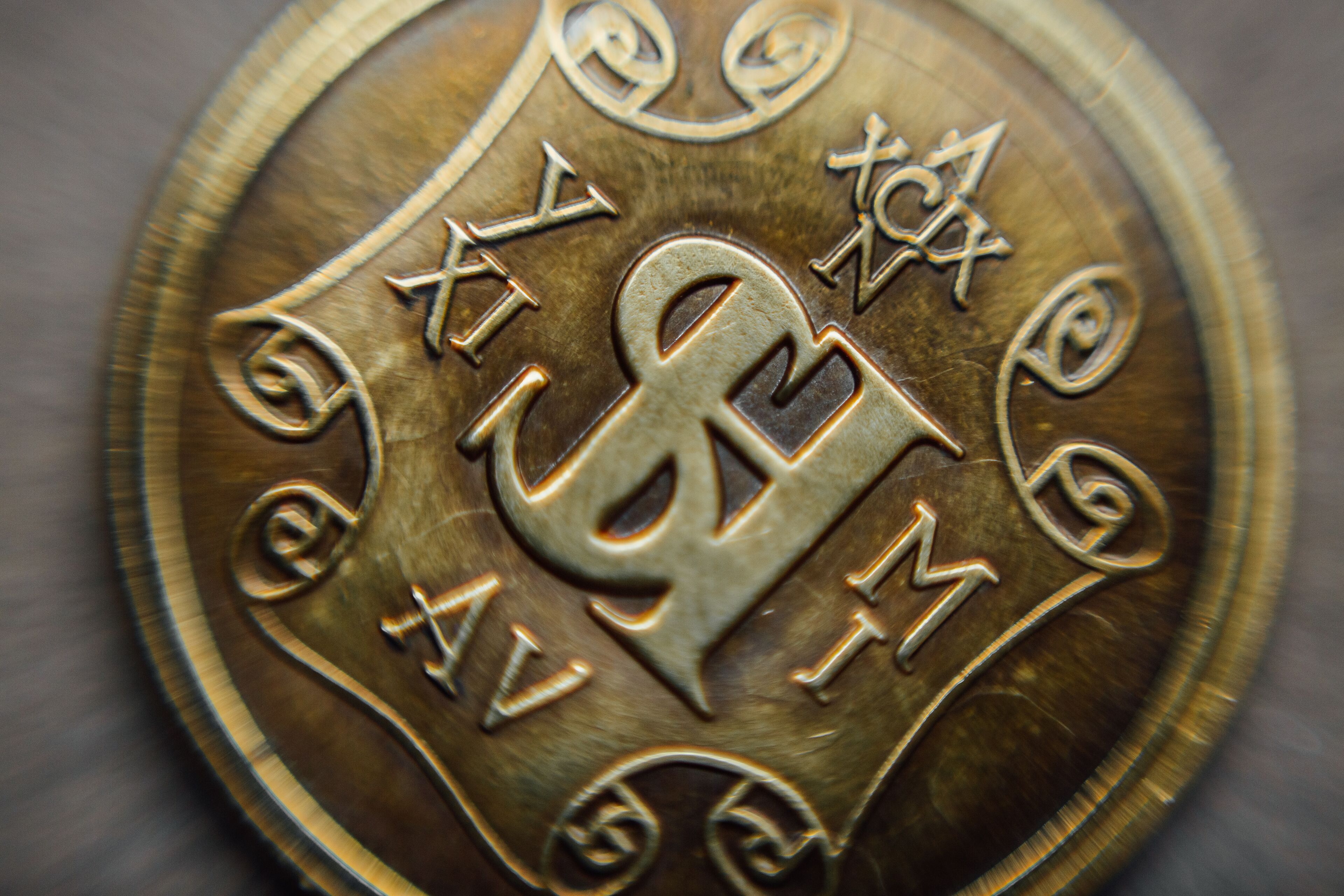 A close-up of a metallic coin with engraved letters and symbols.