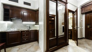 A kitchen with dark wooden cabinets, a countertop with a range hood, and a tiled floor. - Apart-hotel Horowitz (Lviv)