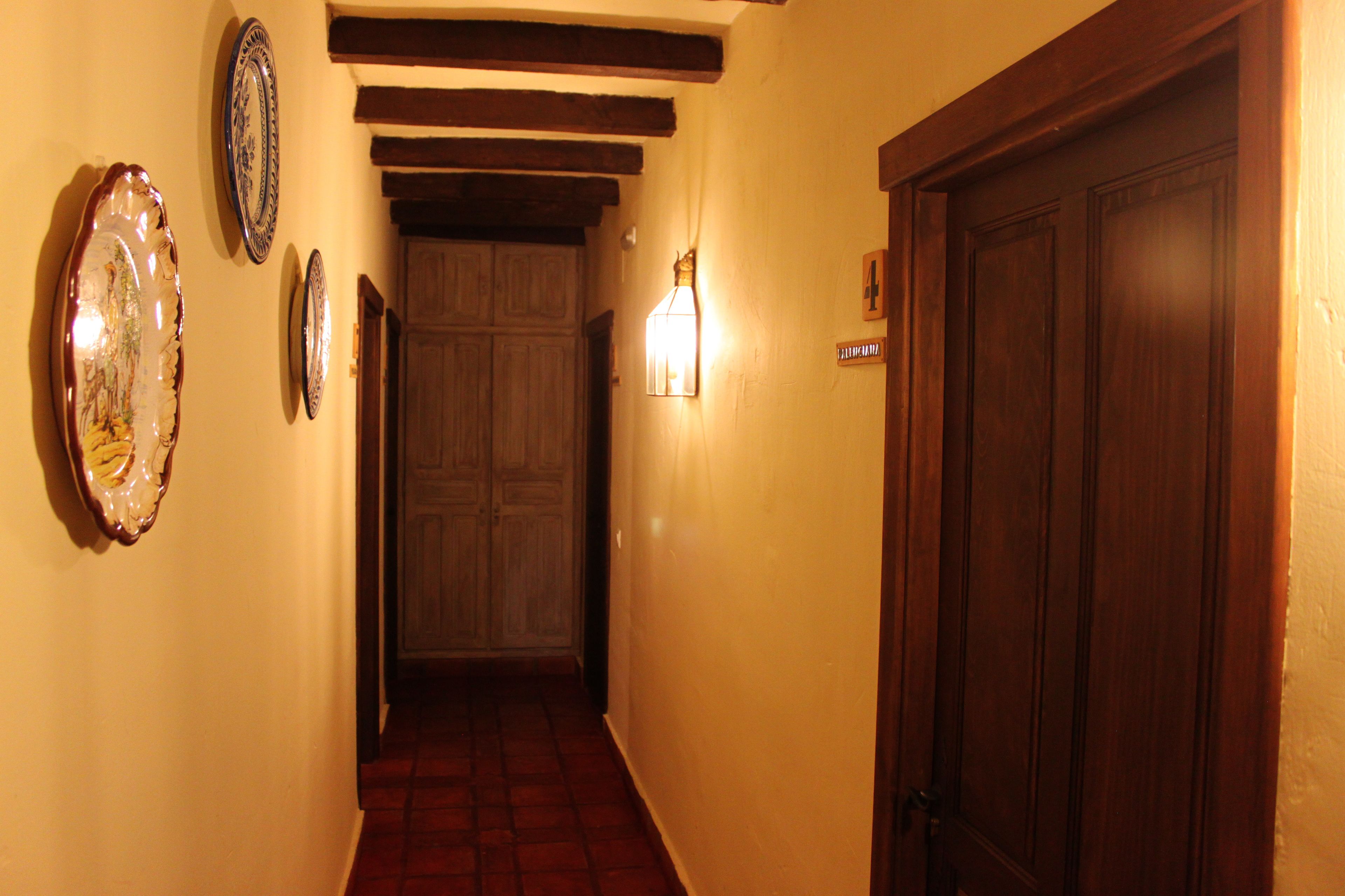 A hallway with wooden beams, a tiled floor, and a door with a number sign.