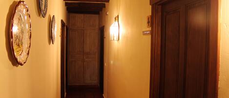 A hallway with wooden beams, a tiled floor, and a door with a number sign.