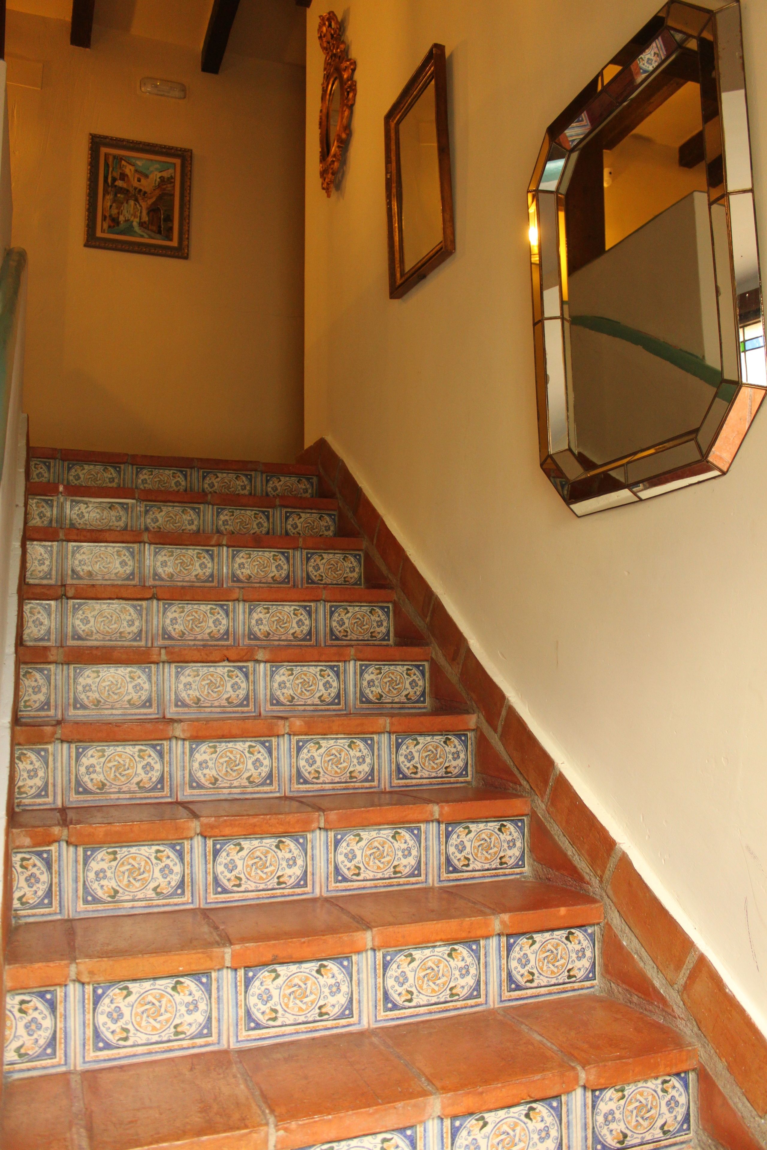 A staircase with ornate tiles and a mirror on the wall.