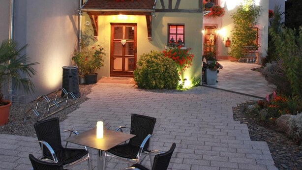 A traditional half-timbered house with a paved patio and outdoor seating. - Hôtel les Portes de la Vallée (Turckheim)