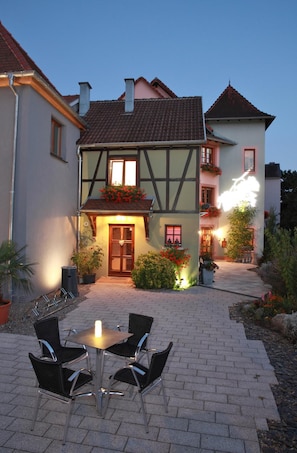 A traditional half-timbered house with a paved patio and outdoor seating. - Hôtel les Portes de la Vallée (Turckheim)