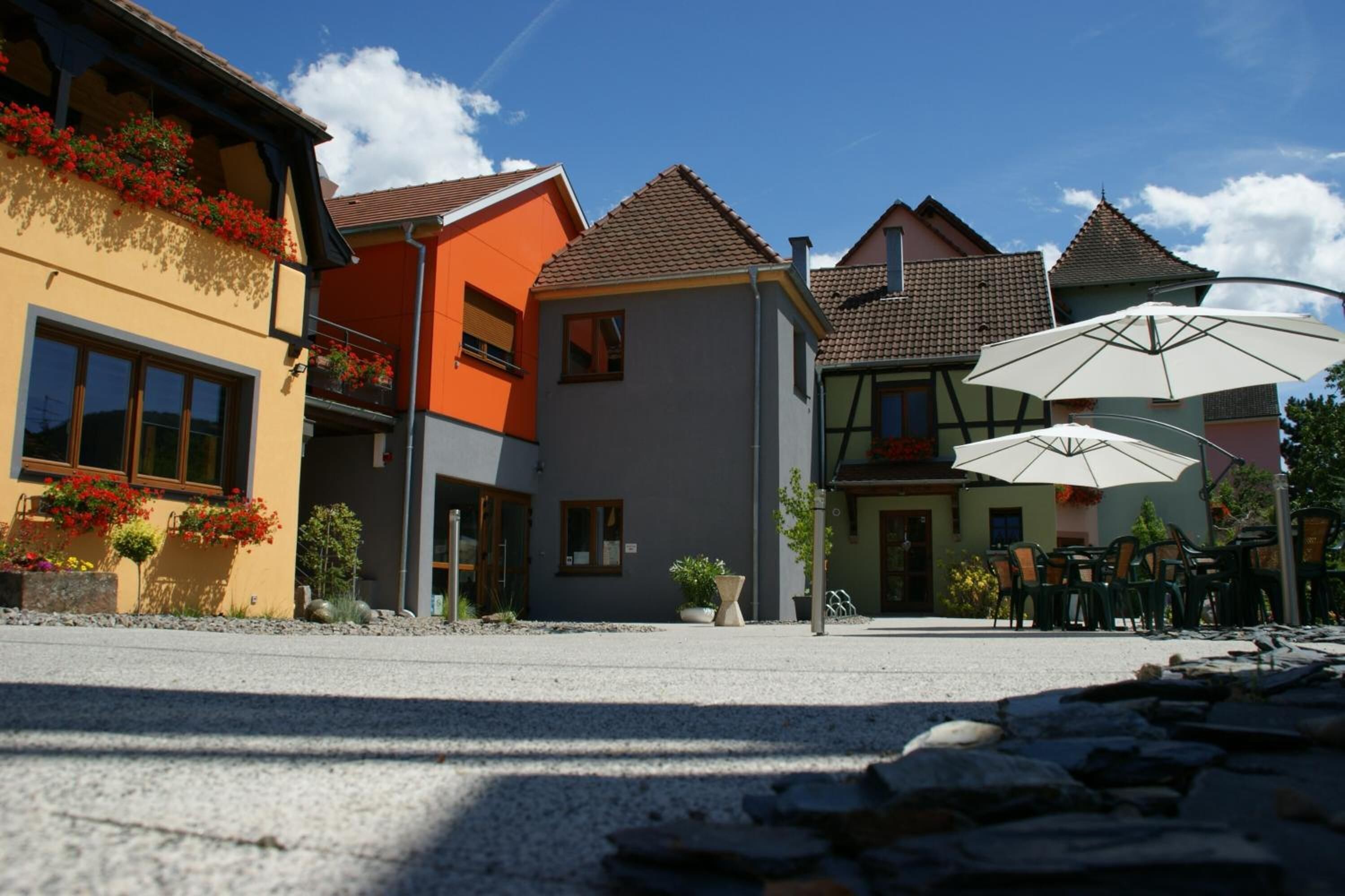 A street with colorful buildings, outdoor seating, and a gravel path.