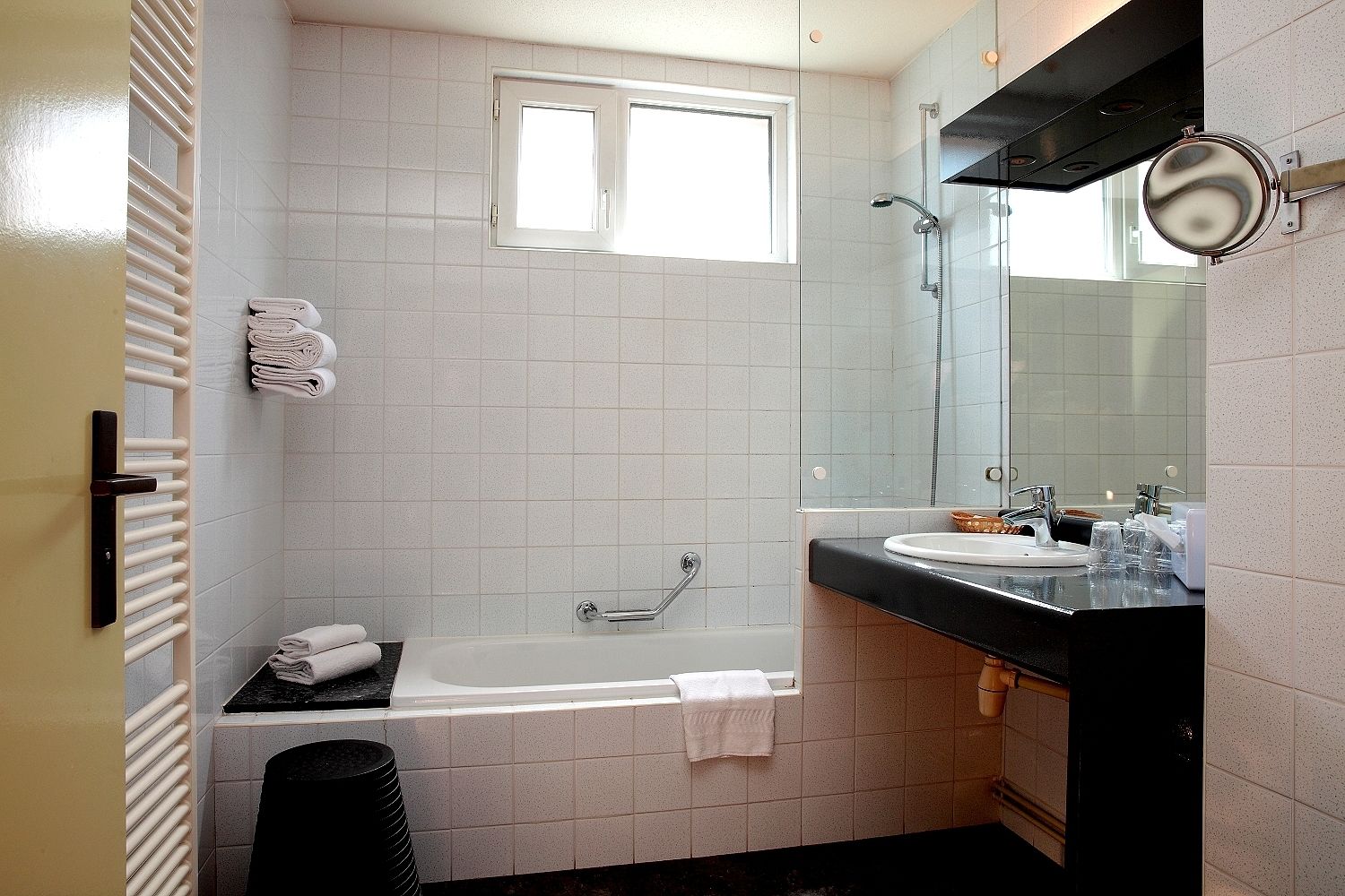 A modern bathroom with a bathtub, a sink, and a large mirror.