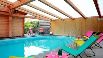 Una piscina al aire libre, sillones reclinables de piscina