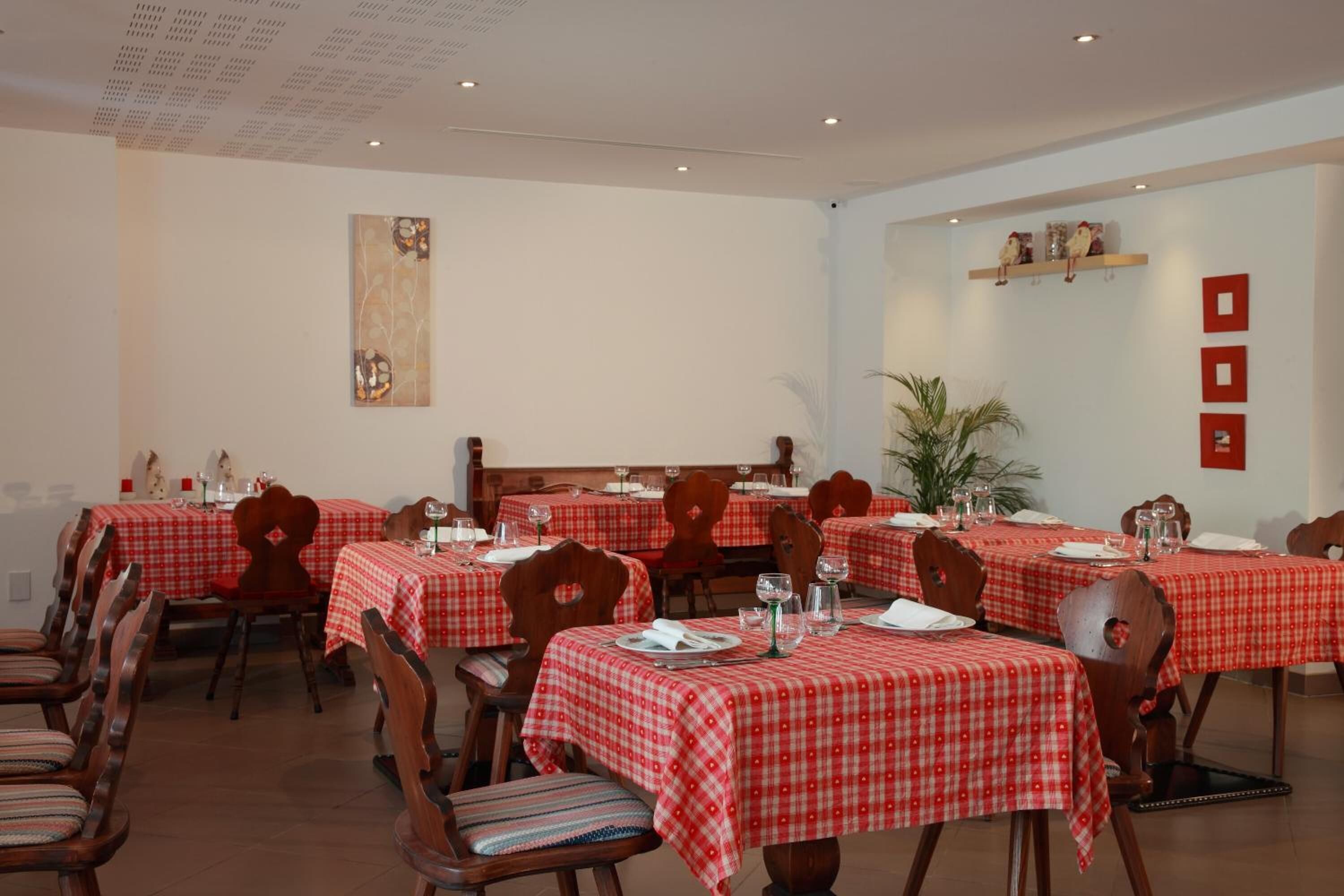 Un coin repas avec des nappes à carreaux rouges et blancs, des chaises en bois et une plante en pot.
