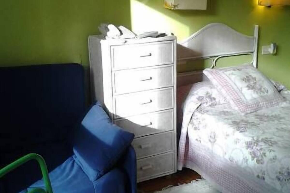 A room with a bed, a dresser, and a chair.