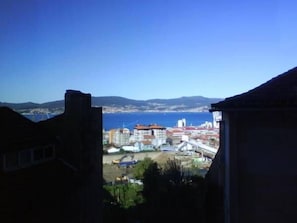 A coastal cityscape with buildings, a clear blue sky, and a view of the sea. - Hotel Solpor (Vigo)
