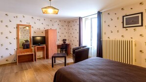 Une chambre d’hôtel comprenant un lit, un bureau avec une chaise, une télévision et un radiateur.