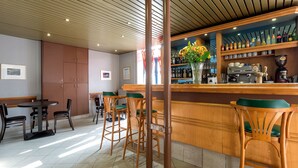 Un restaurant avec des tabourets de bar en bois, un comptoir avec une machine à café et une variété de bouteilles exposées sur des étagères.