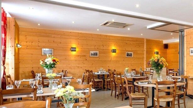 Un restaurant aux murs et aux tables en bois, préparé pour le service.