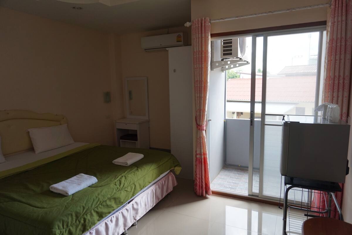 Habitación de hotel con cama, escritorio, silla y vistas al exterior.