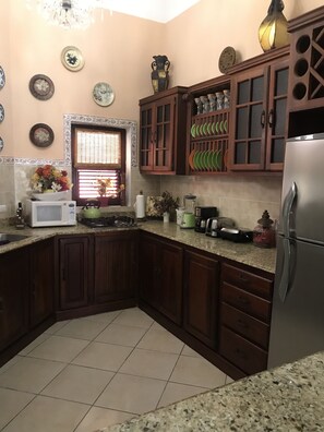 A kitchen with wooden cabinets, a stainless steel refrigerator, a microwave, and various kitchen appliances. - Mariposa (Sosúa)