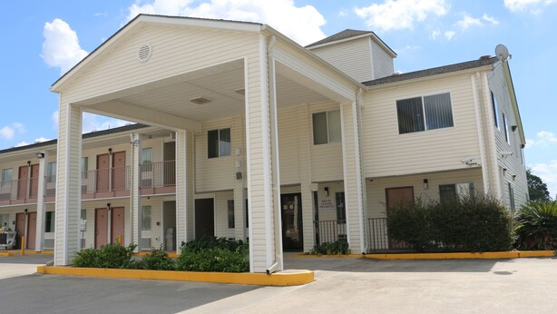 A multi-story motel with a covered entrance and a sign indicating a cooking facility. - Western Inn (Gonzales)