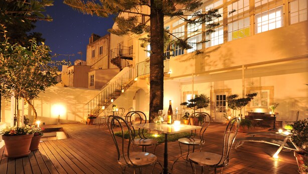 An outdoor patio with a table and chairs, surrounded by potted plants and a staircase leading to an upper level. - Fonte da Foz Bed & Breakfast Terrace (Figueira da Foz)