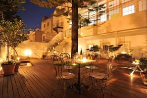 An outdoor patio with a table and chairs, surrounded by potted plants and a staircase leading to an upper level. - Fonte da Foz Bed & Breakfast Terrace (Figueira da Foz)